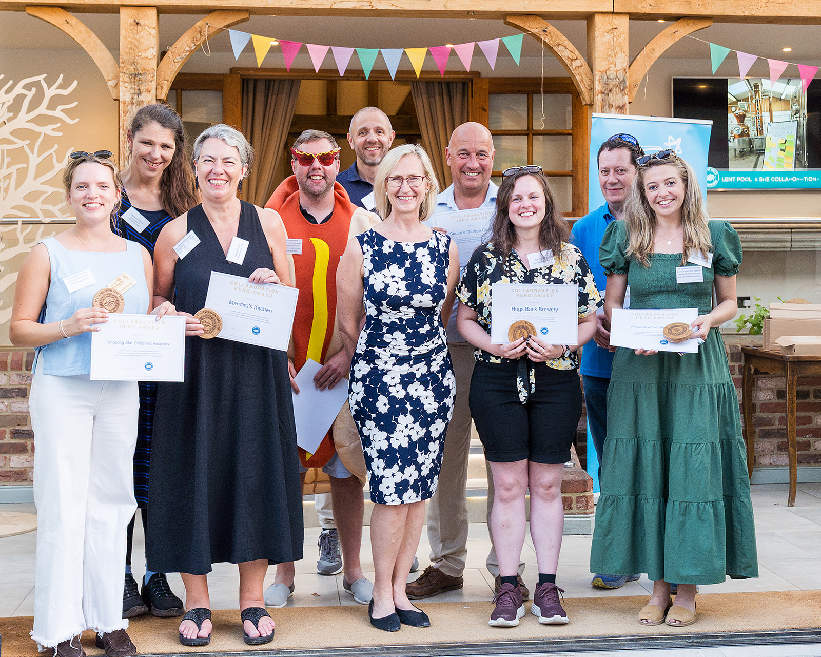 Surrey Hills Enterprises members holding their Collaboration Hero Award certificates at the 2026 summer event